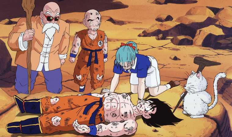 Goku lies defeated and battered, surrounded by friends