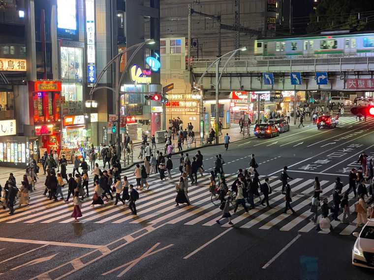 "Photograph of the pedestrian crossing near Ueno, going towards Ameyoko shopping district. It's night time and there are many people."