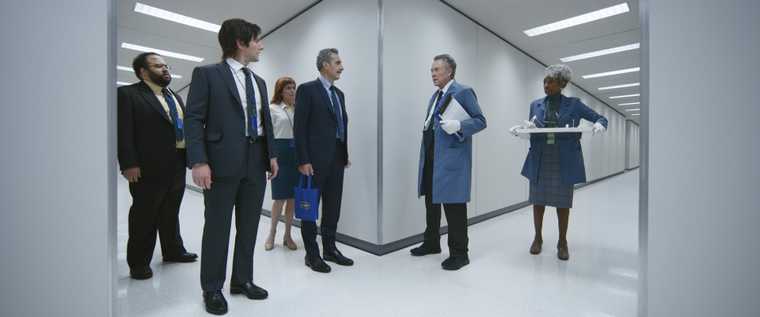 "Screen from Severance TV show. Numerous corporate staff meet at a corridor junction in a tense standoff."