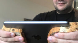 Bearded man holding an iPad Mini between two slices of bread - to emulate the form factor of a Nintendo Switch.