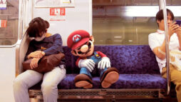 Promotional screen from Nintendo. A photograph of the inside of a Tokyo subway car, featuring a computer generated image of game character, Mario, asleep.