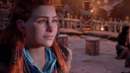 Promotional screen from Horizon Zero Dawn. A young red haired woman (Aloy) looks towards the screen.