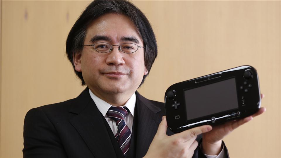 Photography of Japanese game developer, Satoru Iwata, wearing a suit and holding a Nintendo Wii U.