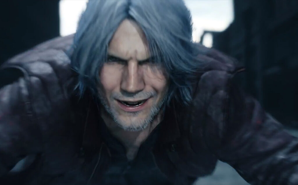 Screenshot from E3 2018's Devil May Cry 5 trailer by Capcom. Close up of grizzled, older male character, smiling maniacally.