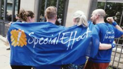 A photograph of 4 runners from behind, after completing a 10km route. Holding a flag for gaming charity, Special Effect.