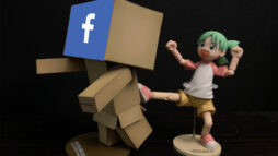 A composed scene with two posable toys. One, a robot made from cardboard boxes, with the Facebook logo imposed on its face. The second, a young girl with green hair kicking the robot from behind. It's a visual metaphor for "kicking social media".