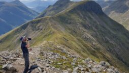 A man looking towards Glencoe from the ridge along Buachaille Etive Mòr, Glencoe.