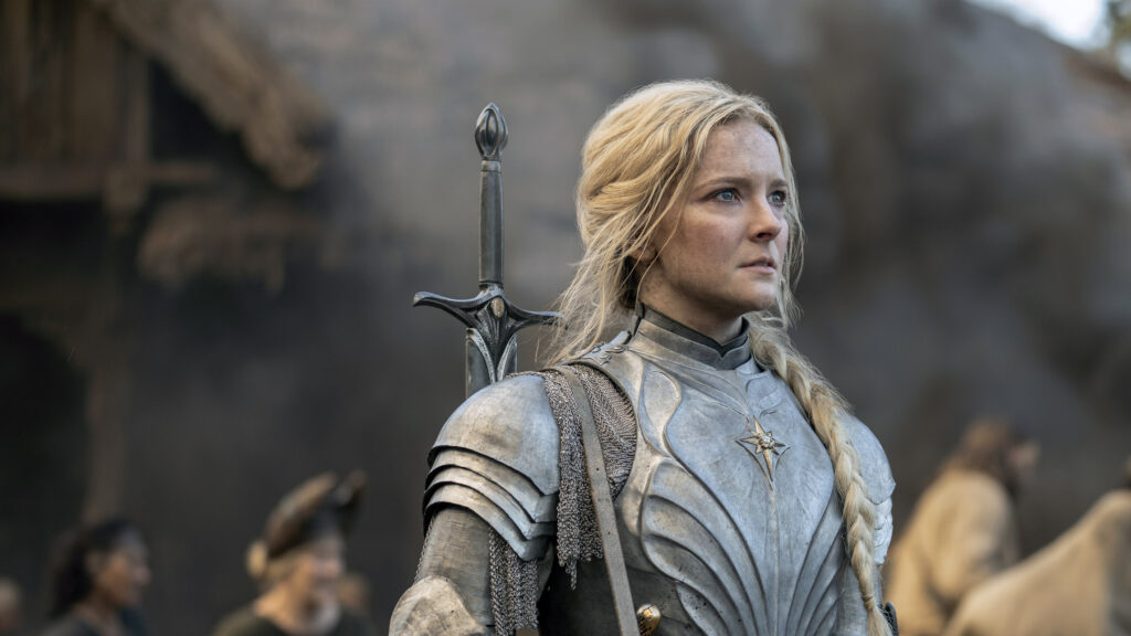 Screen from The Lord of the Rings: The Rings of Power TV show. Galadriel played by Morfydd Clark wearing armour and staring intensely.