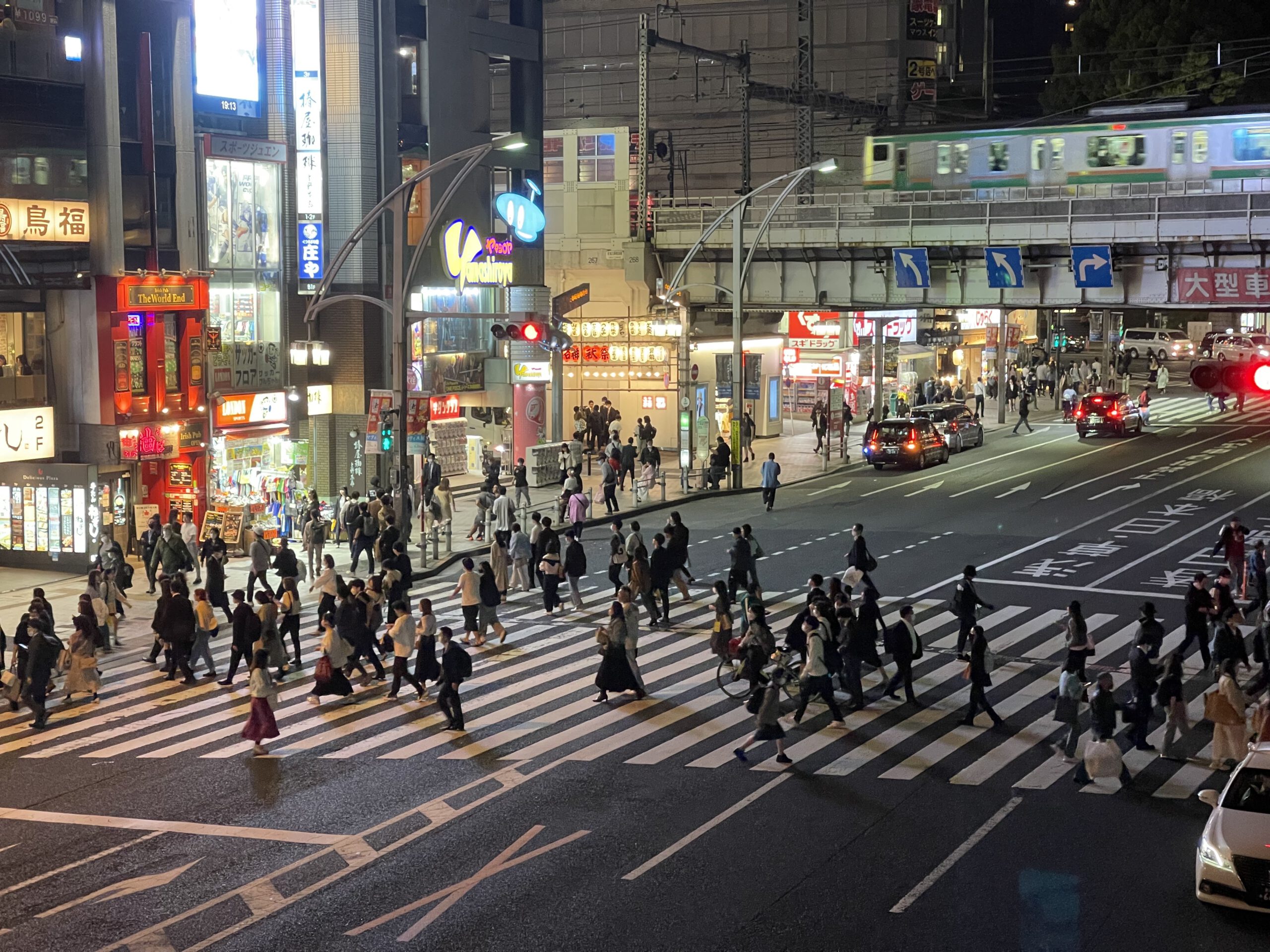 Photograph of the pedestrian crossing near Ueno, going towards Ameyoko shopping district. It's night time and there are many people.