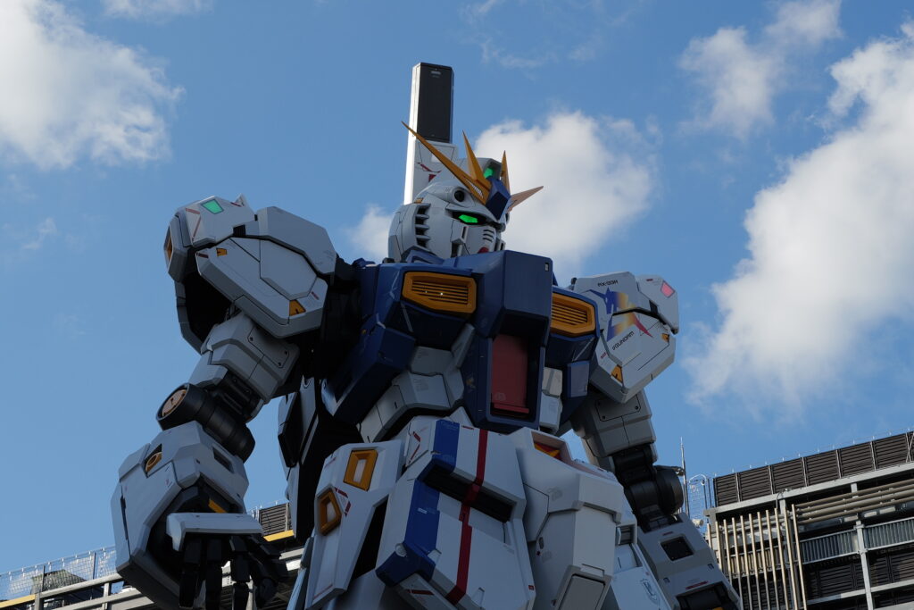 A life-sized mechanoid statue standing against a blue sky.