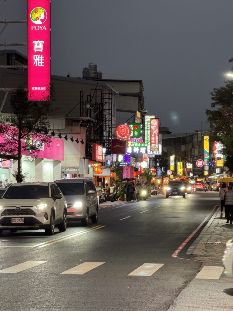 Jiaoxi at night. A lit up street with various neon signs.