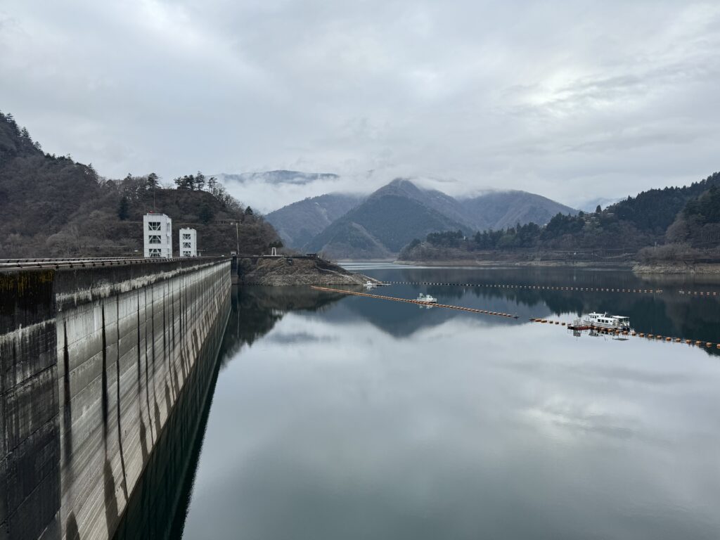 A reservoir and dam. In the background, mountains and forests.