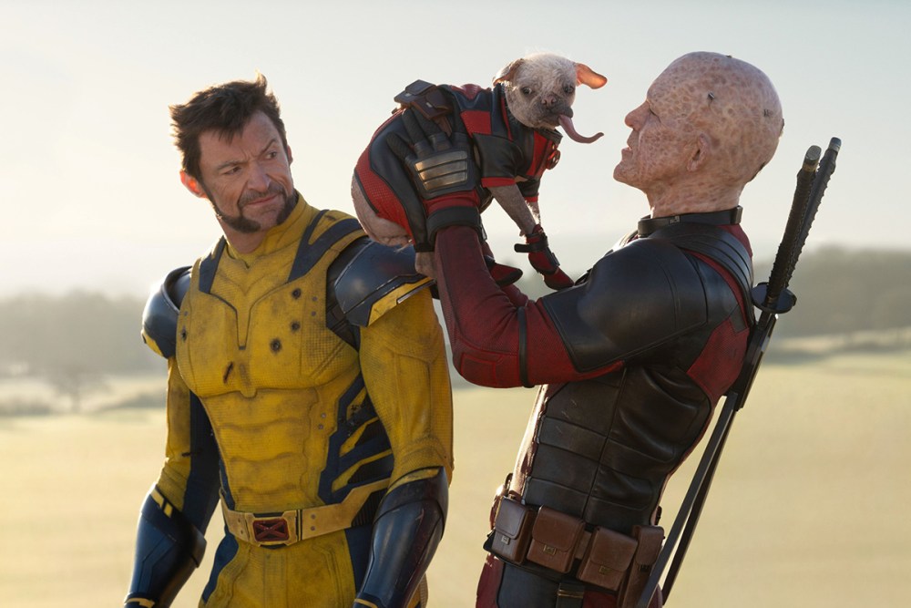 Screen from Deadpool & Wolverine. Man in red jumpsuit (Ryan Reynolds) holding a dog whilst man in yellow jumpsuit (Hugh Jackman) looks bemused.