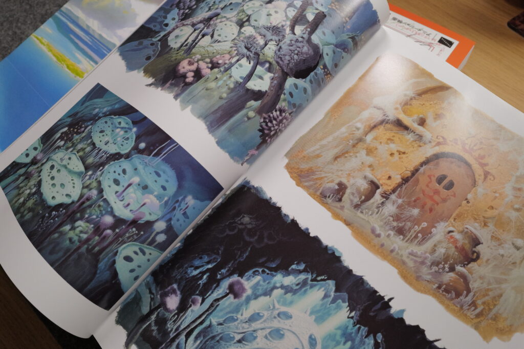 Photograph of a page from Painting the Worlds of Studio Ghibli book, featuring beautiful paintings from their animated films.